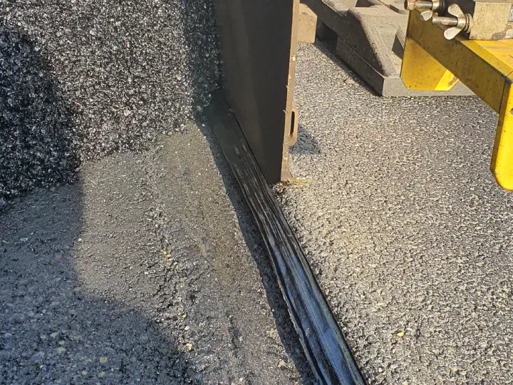 The paver working along the edge of the adjacent lane.